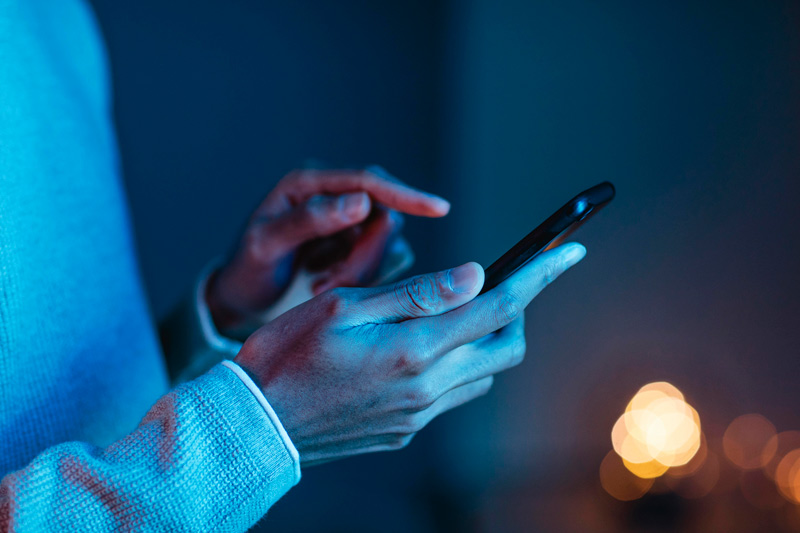 Seitenansicht auf Hände die auf einem Smartphone tippen