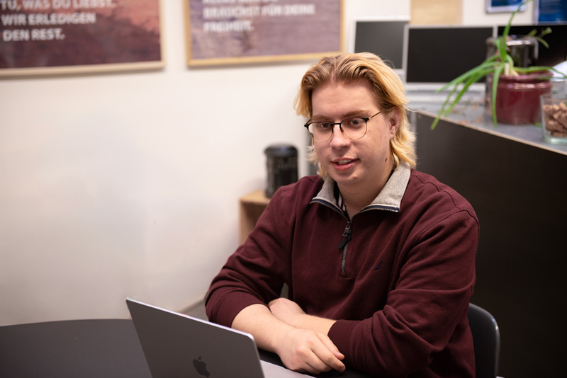 Junger Mann sitzt vor Laptop